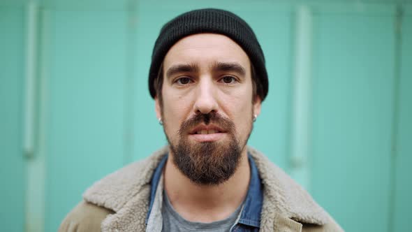 Concentrated bearded man wearing hat looking at the camera