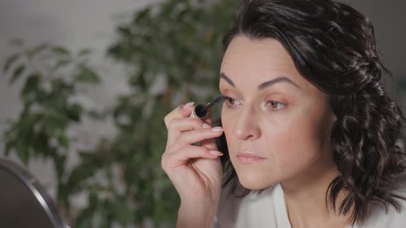 Applying the Morning's Makeup. The Brunette Creates a Face Drawing for Herself Before Leaving for