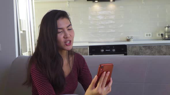 Asian Girl Communicates on a Smartphone