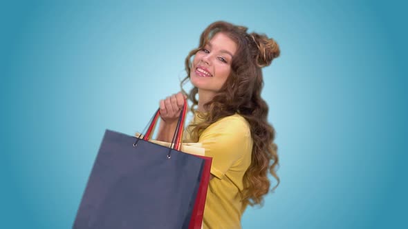 Attractive Young Girl with Shopping Bags Spinning Around Herself and Posing Looking at the Camera