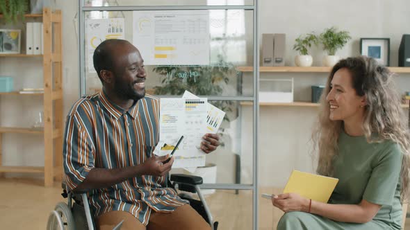 Afro Man with Disability Discussing Business Report with Colleagues