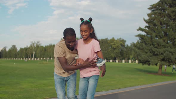 Dad Helping Teenage Girl To Ride Roller Skates