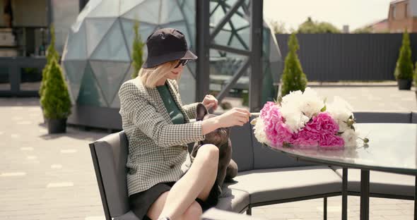 Young Casually Dressed Woman Sitting at Cafe with Her Bulldog Puppy