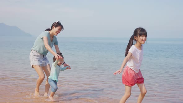 Happy Asian family, Mother playing and having fun with children on the beach during holiday vacation