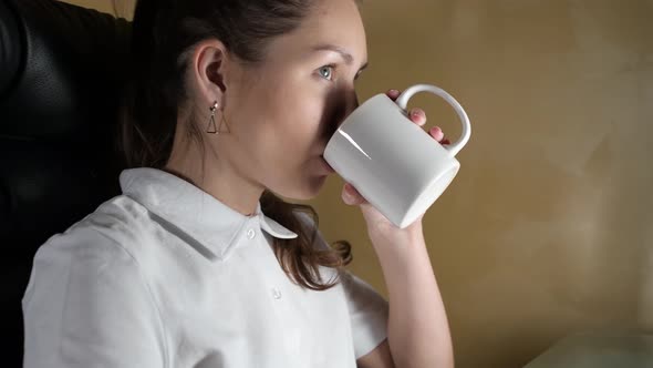 girl who works at a computer and drinks a hot drink - tea or coffee