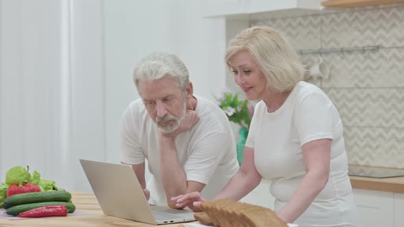 Loving Old Couple Working on Laptop in Kitchen