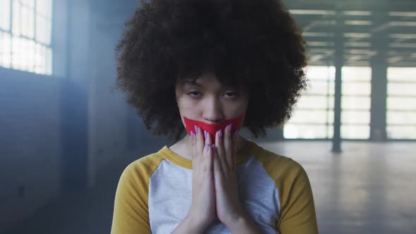 Portrait of african american woman with red tape on her mouth in empty parking garage