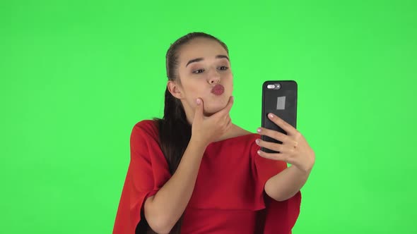 Portrait of Pretty Young Woman Is Making Selfie on Mobile Phone Then Looking Photos. Green Screen