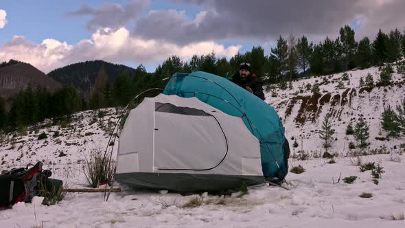 Hiker pitching tent in winter in the mountains.