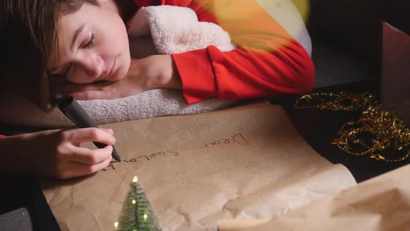 Teenage Boy Writing Long Letter To Santa