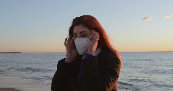 Girl with Red Hair Takes Off Her Mask and Breathes Clean Air Near the Ocean