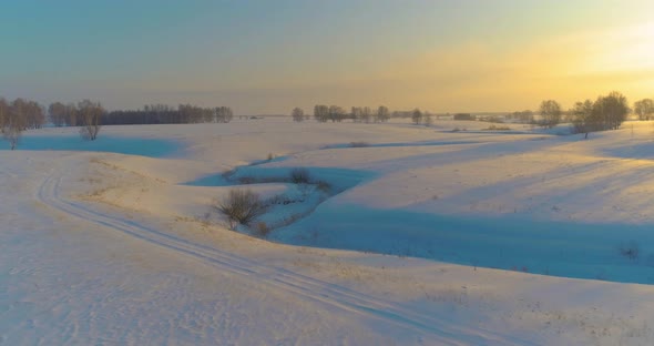 Aerial View of Cold Arctic Field Landscape Trees with Frost Snow Ice River and Sun Rays Over Horizon