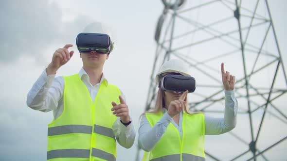 Two Engineers of Power Engineers in VR Glasses Move Their Hands Simulating the Operation of the