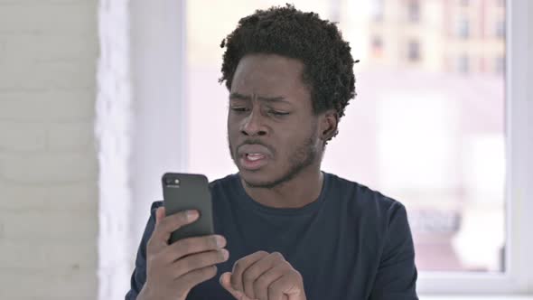 Portrait of Young African American Man Shocked Using Smartphone