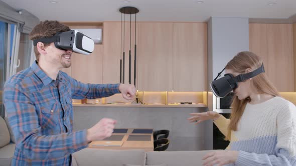 Man and a woman, use a VR helmet at home. People wearing glasses and a virtual reality helmet.