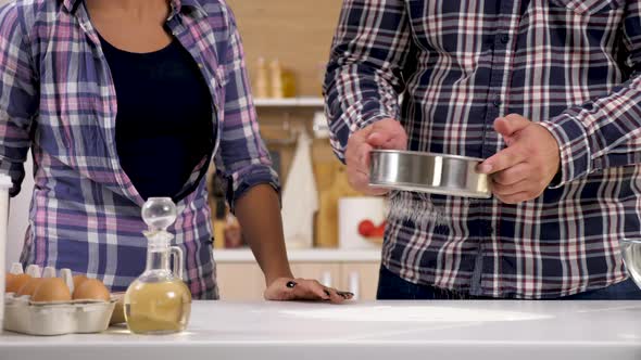 Couple in the Kitchen Sift the Flour Through a Sieve