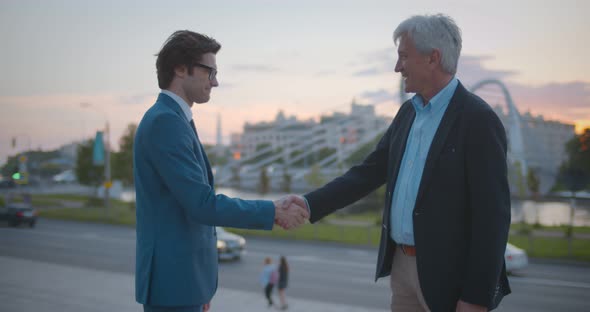 Side View of Business Partners Shaking Hands Outside in Modern City