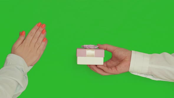 A man gives a woman a nice gift in a box, a woman claps her hands, on chroma key green background