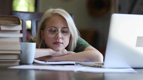 Blonde girl in glasses working with notebook at home as freelancer