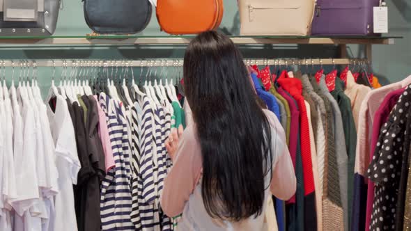 Lovely Woman Smiling To the Camera While Shopping for Clothes