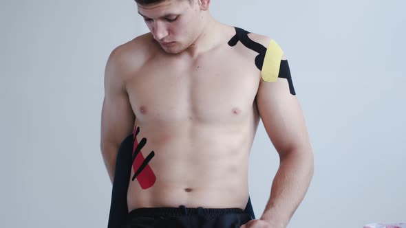 Shirtless Athlete with Kinesiology Tape on Shoulder in Clinic