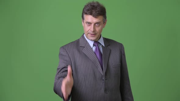 Mature Handsome Businessman Against Green Background