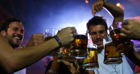 Group of friends toasting beer mugs at a concert 4k