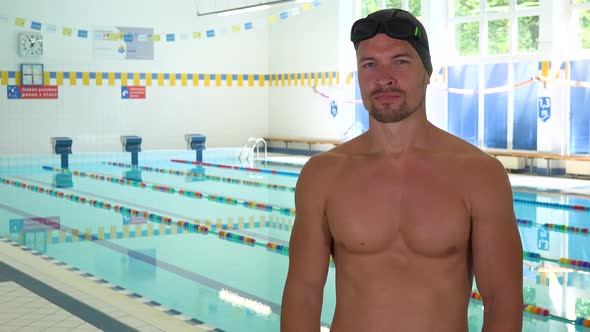 A Professional Swimmer Points at the Camera and Nods at an Indoor Pool