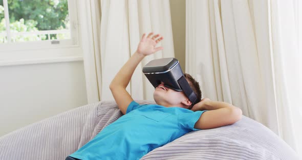 Caucasian boy wearing vr headset while lying on the bean bag at home