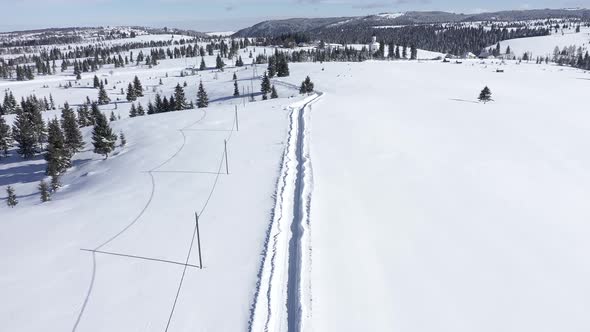 Flying Above Snow Covered Road in the Mountains