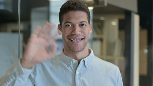 Young African Man Waving and Smiling at Camera