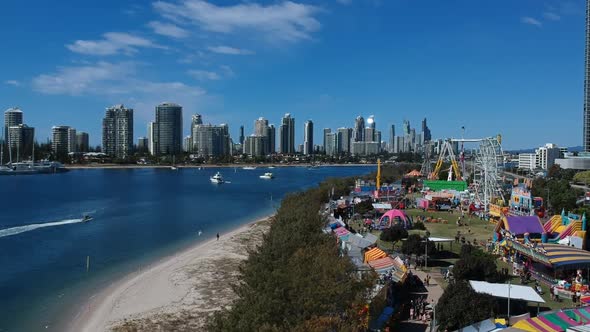 Aerial view of a colourful carnival situated by the sea with a city skyline in the background