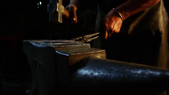 Mid-section of blacksmith working on a horseshoe