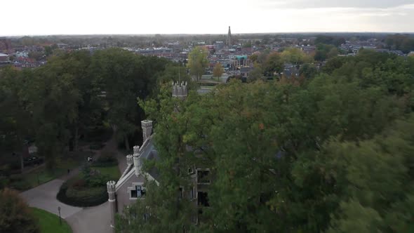 Aerial over trees and beautiful mansion, reveal a busy road near a small city