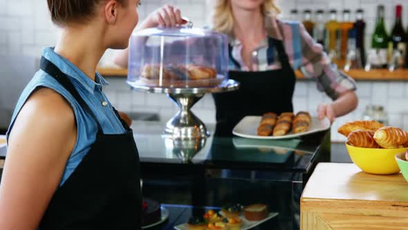 Waitress standing at counter while colleague working in the background