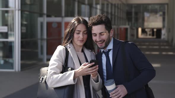 Smiling business couple taking smartphone selfie in the street