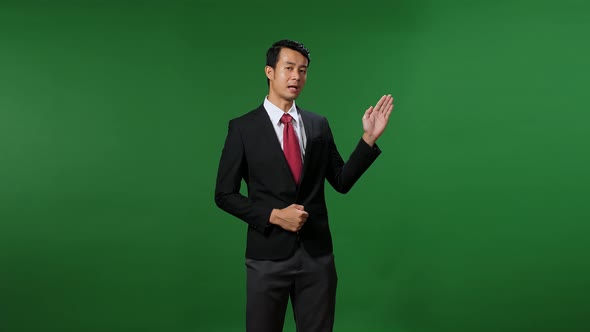 Young Asian Businessman In Suit Jacket Standing And Presenting Something On Green Screen Background