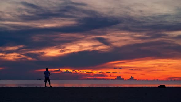 A Young Couple Is Playing with a Flying Saucer on the Beach at Sunset