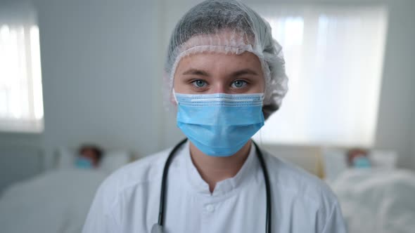 Closeup Woman in Coronavirus Uniform Looking at Camera Leaving Hospital Ward with Ill Patients at