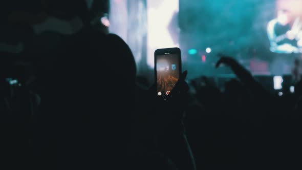 Woman Hands Silhouette Recording Video of Live Music Concert with Smartphone