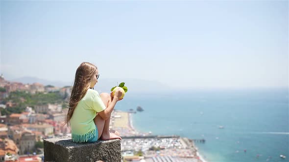 Big Yellow Lemon in Hand in Background of Mediterranean Sea and Sky.