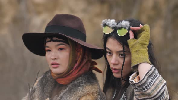 two Asian young women in ethnic clothes are embracing and posing in the steppe in nature. Slow motio