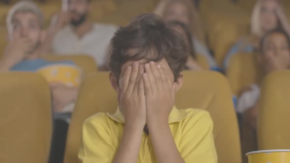 Portrait of Scared Middle Eastern Boy Closing Eyes in Cinema. Absorbed Child Watching Frightening