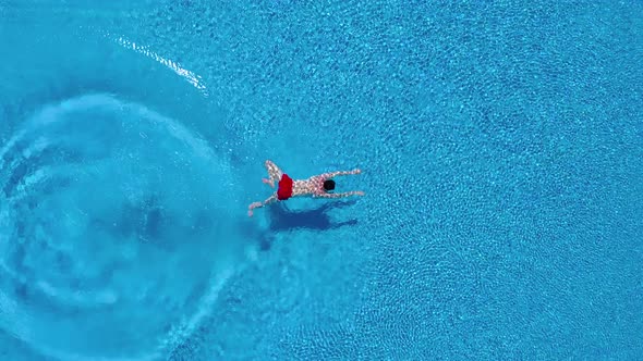 View From the Top As a Man Dives Into the Pool and Swims Under the Water