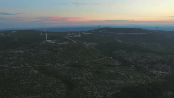 Aerial view of dozen windmills for the production of electric energy, at sunset