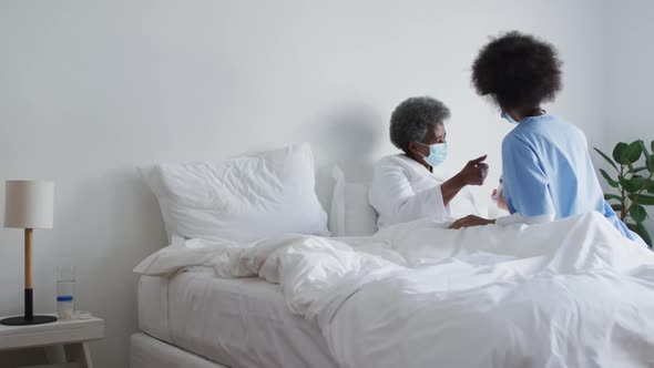 African american female doctor and senior female patient in face masks