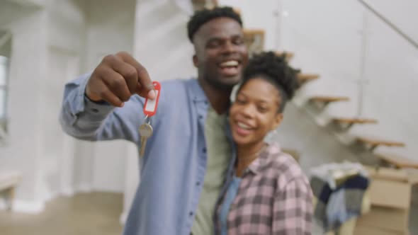 Video of happy african american couple embracing, showing keys to new house