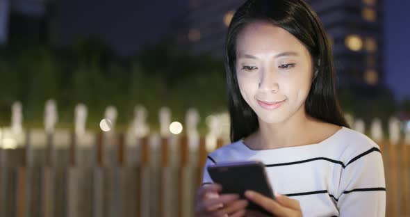 Woman looking at mobile phone in city at night