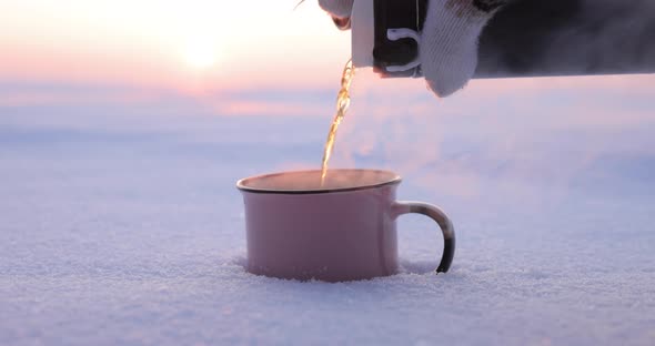 Pours Tea From a Thermos Into a Cup on a Snowy Day