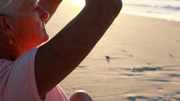 Senior woman doing yoga on the beach